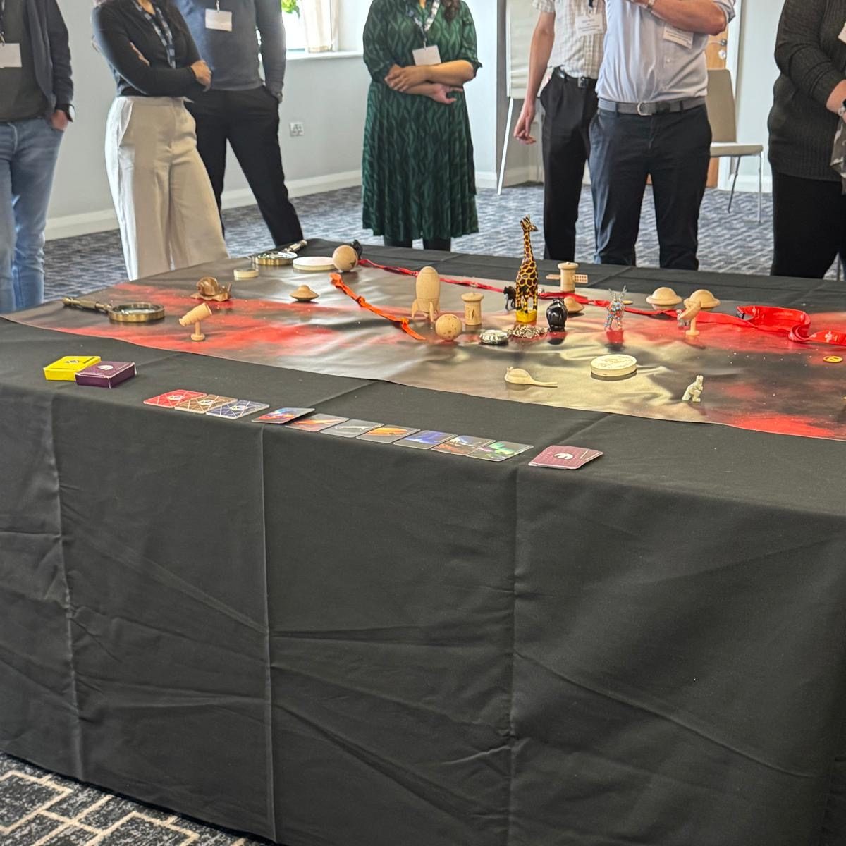Mid Strategic Orbits Exercise®, clients stand around a table with the SOE map and artefacts arranged on it deep in discussion.